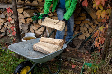 Man working hard in his backyard collecting the heavy pieces of firewood and putting it on the...