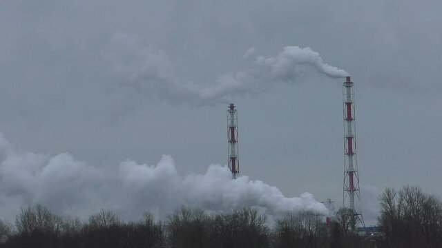 Water vapor comes out of the factory pipes. Damage to the environment and climate due to the greenhouse effect of human production.