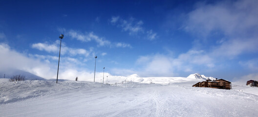 Panoramic view on snowy ski slope and hotel in high winter mountains