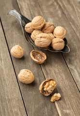 Walnuts over a wooden table and into an old metal bowl