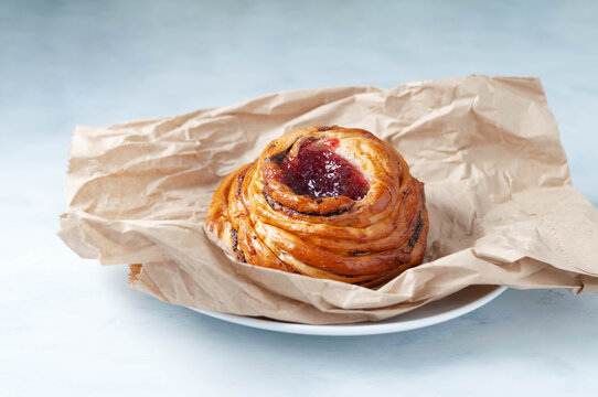 Tasty Crispy Bun With Red Cherry Jam On Craft Paper On Plate