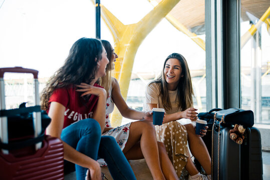 Merry friends talking while waiting for flight in airport - Powered by Adobe