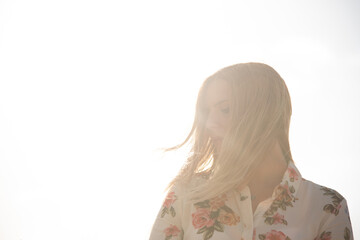 Chica rubia con camisa con el sol de fondo. 
