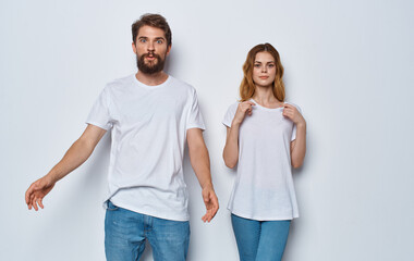 Fototapeta premium A guy and a beautiful woman in the same clothes on a light background are gesticulating with their hands 