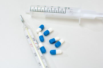 Medical thermometer, syringe and pills isolated on white background
