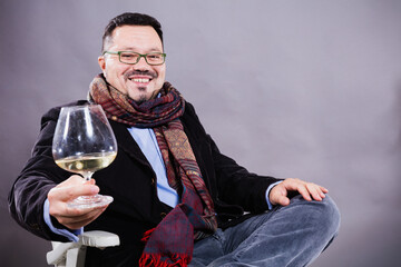 Solid cheerful man in kerchief sitting with glass of wine