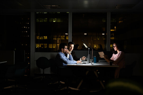 Cheerful young group of colleagues working late in office