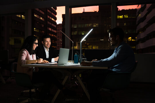 Cheerful young group of colleagues working late in office