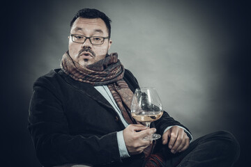 Solid cheerful man in kerchief sitting with glass of wine