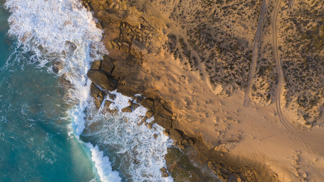 Aerial view of the beach with footprints in the orange sand and aqua-colored ocean. Top view, amazing nature beach background. Atlantic ocean in Zahora, Cadiz, Andalusia, Spain.