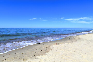 Calm blue Baltic sea and blue sky. A small long wide wave is approaching the sandy shore.. Donskoye, Svetlogorsk District