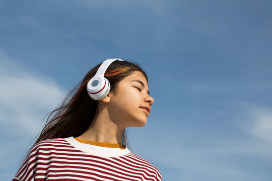 Girl with a headphones on a blue sky background
