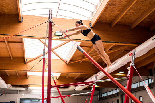 young artistic gymnast woman performing and training uneven bars