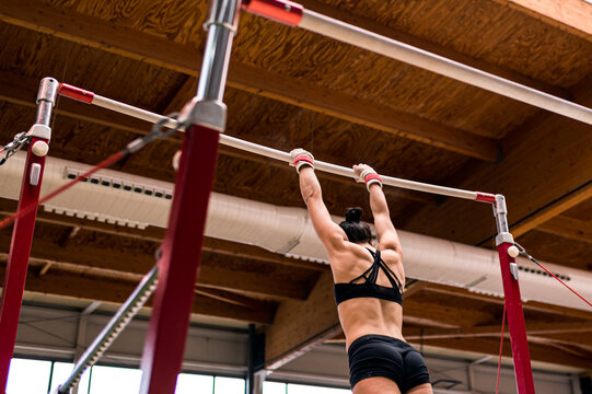 young artistic gymnast woman performing and training uneven bars