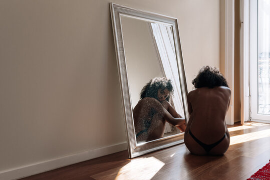 Melancholic Ethnic Young Woman On Floor Beside Large Mirror With No Pants