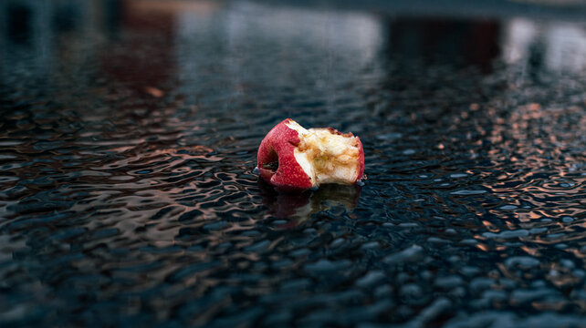 bitten apple in a puddle on the street floor with beautiful lights and colors