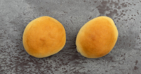 Two homemade yeast rolls on a gray background top view.
