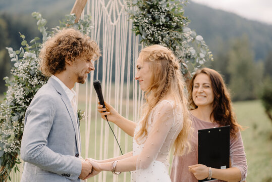 master of ceremonies holds a microphone while the groom says the oath to the bride