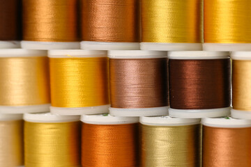 Bright colourful flat lay with lots of spoools for sewing with metal yellow and golden threads, flat lay