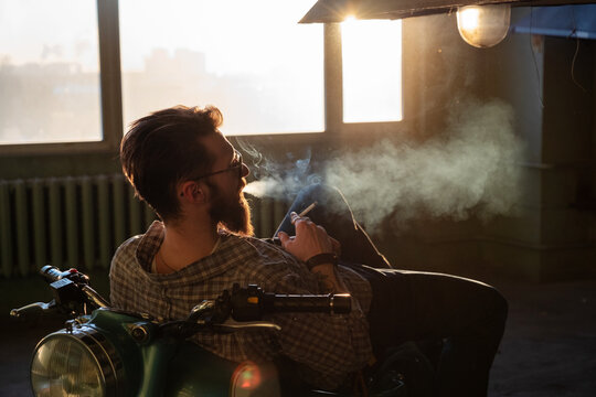A bearded man smokes a cigarette
