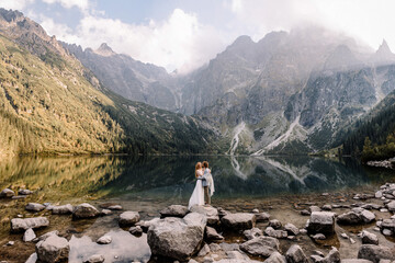 Just married couple on the background of large-scale panoramic view of mountain lake