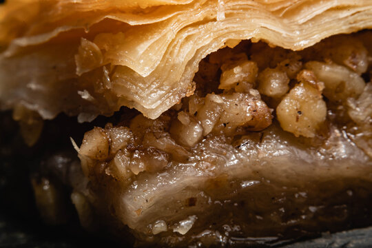 primer plano macro de baklava pastel típico y tradicional turco masa hojaldrada y nuez y pistacho triturado con miel y almíbar de azúcar sobre plato de piedra laja negra