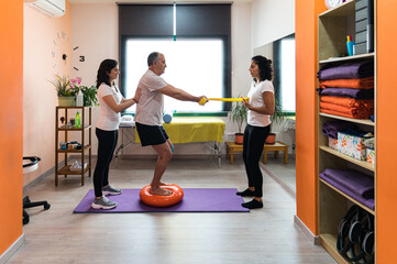 Senior man doing physiotherapy exercise with therapists