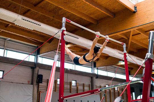 young artistic gymnast woman performing and training uneven bars