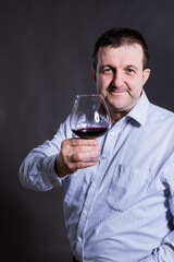 Middle aged cheerful man dressed in a shirt with glass of wine