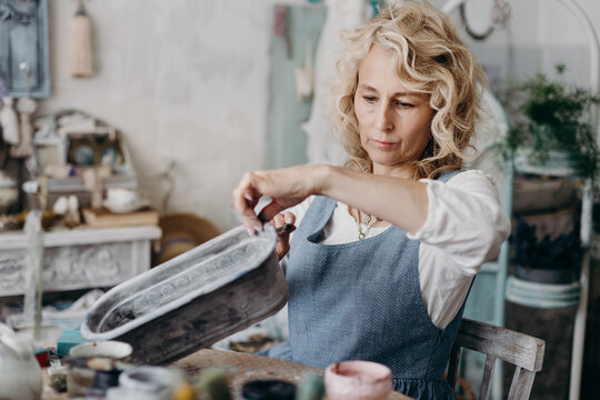 Mature craftswoman painting handmade pot