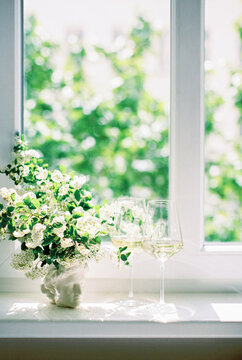 bouquet of white flowers in a vase and two wineglasses