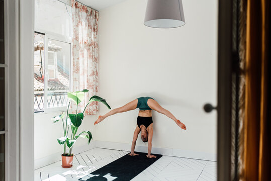 Flexible woman doing splits in handstand