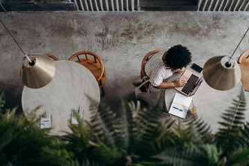 Top view of a black young woman using laptop in a stylish cafe interior.