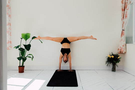 Flexible woman doing splits in handstand