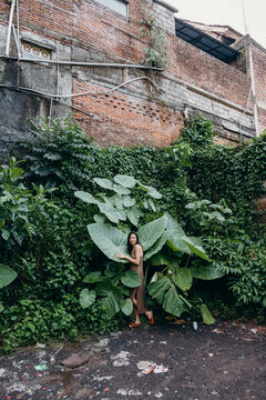 Asian girl posing among tropical plants and trash