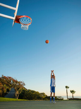 Black teenage boy shooting basketball on court