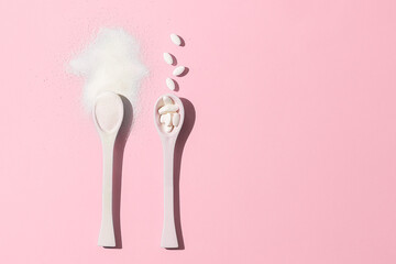 Spoons with collagen on pink background with a copy of space.
