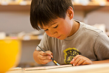 Mixed Race boy painting in art class
