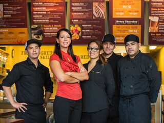 Hispanic business owner and employees smiling in cafe