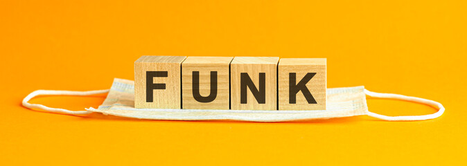 funk the word is written on wooden cubes lying on a medical face mask. Concept. yellow background