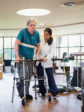 Physical therapist helping man using walker