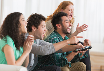 Friends watching television together on sofa