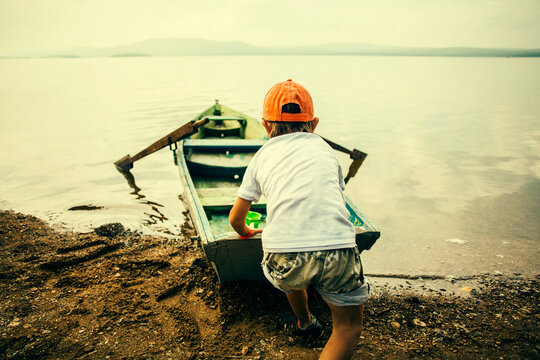 Caucasian boy pushing boat into still lake