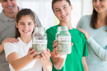 Proud Caucasian parents watching children with college savings jars