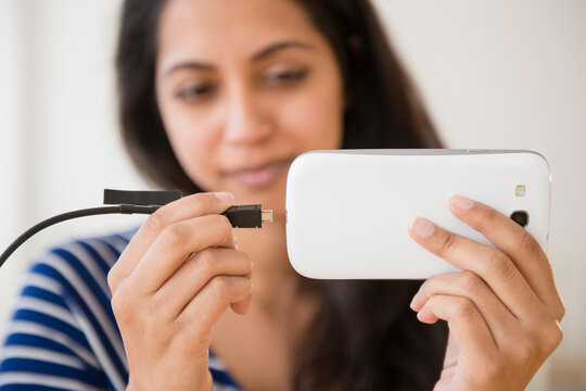Close up of Asian woman connecting cell phone to battery