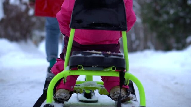 Mom rides a child on a sleigh in the winter forest. Winter games in the snow. High quality FullHD footage