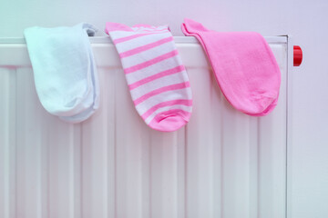 Cotton socks drying on a radiator of central heating, wet clothes hanging on a heater after washing and laundry, clean clothing after wasing machine