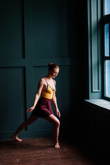 Fototapeta na wymiar Ballerina in dark bodysuit, in dress in dark interior Studio. Wall of bricks, piano.