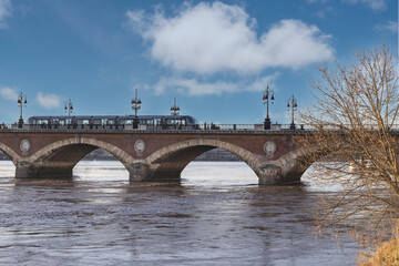 Fototapeta premium Le tramway traversant le pont de pierre de Bordeaux