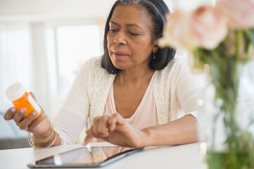 Mixed race woman researching medication on tablet computer